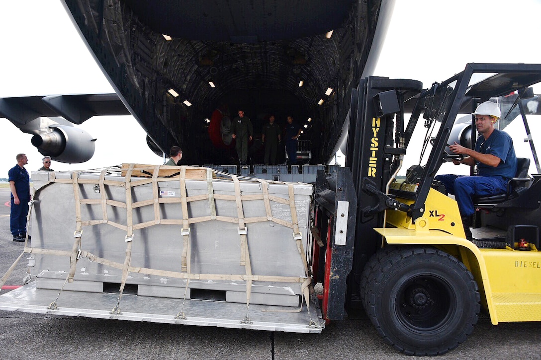 A Coast Guardsman operates a forklift to upload equipment into a C-17 Globemaster III aircraft