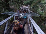 Tech. Sgt. Robert Dones, 349th Medical Squadron surgical technician, lifts up a fence to he broke to allow hikers to escape during a 20-plus hour trek away from the Eagle Creek Trail fire in the Columbia River Gorge near Portland, Ore, on Sept. 2, 2017.  Dones helped guide about 150 hikers from the danger of the fire to safety. (U.S. Air Force courtesy photo provided by Sarah Carlin Ames)