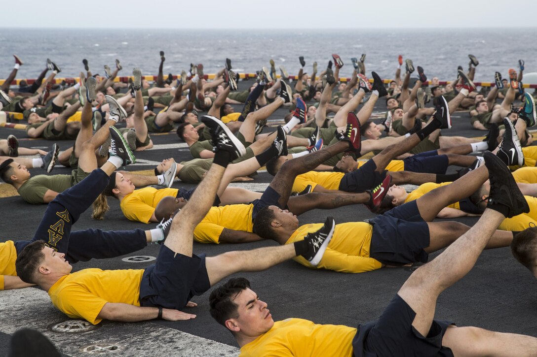 Service members do flutter kicks on a flight deck.