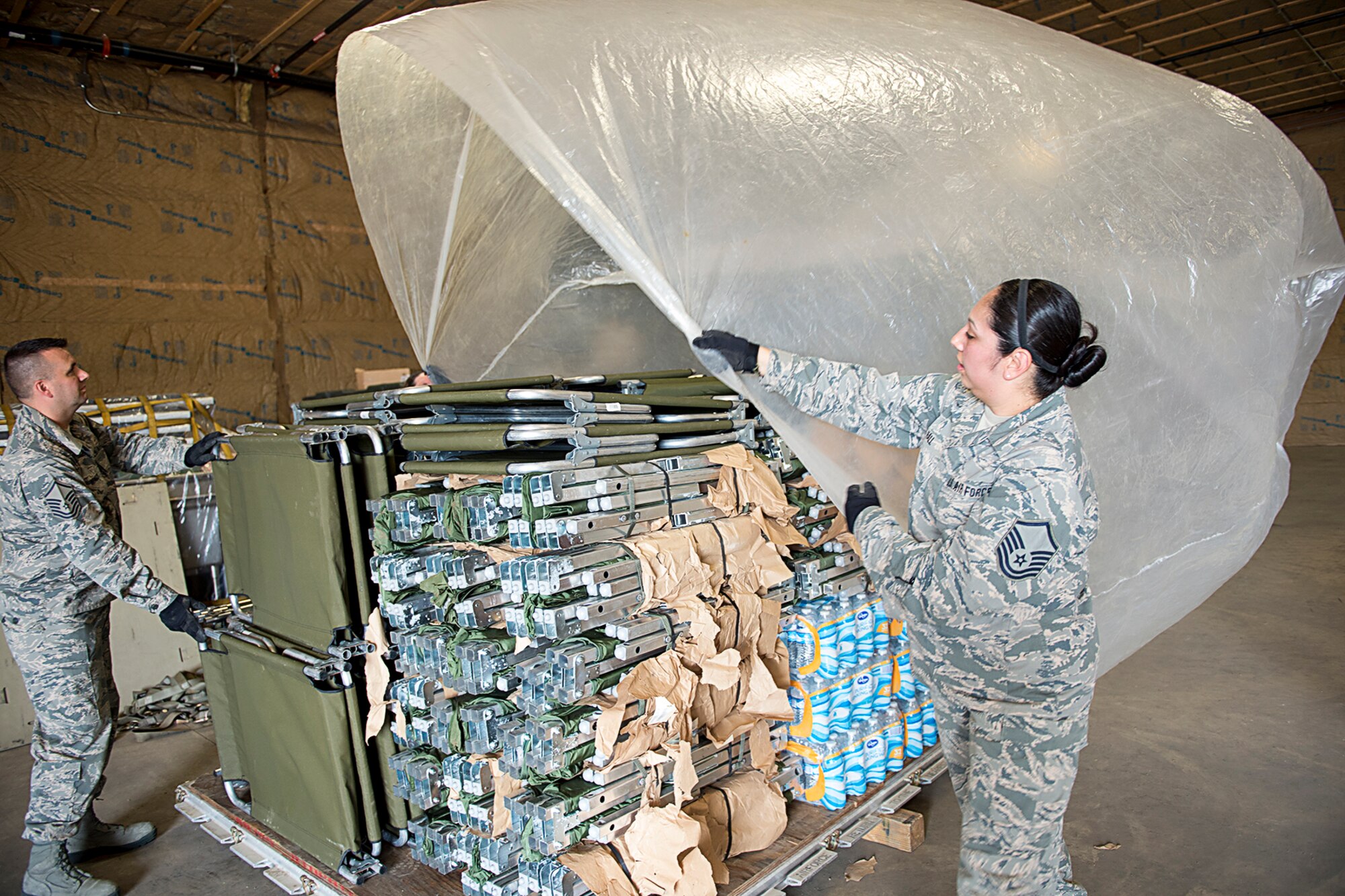 Master Sgt. Angie Hall, 434th Logistics readiness Squadron combat readiness technician, and Master Sgt. Adam Oswalt, 434th LRS training manager, place plastic sheeting on top of cargo at Grissom Air Reserve Base, Ind., Sept. 11, 2017. The pallet of cargo is being prepared for shipment to Florida as part of Hurricane Irma relief efforts. (U.S. Air Force photo/Douglas Hays)