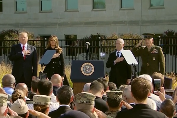 President Donald J. Trump, his wife, Defense Secretary Jim Mattis and the chaiman of the Joint Chiefs of Staff render honors in front of a crowd at the Pentagon.