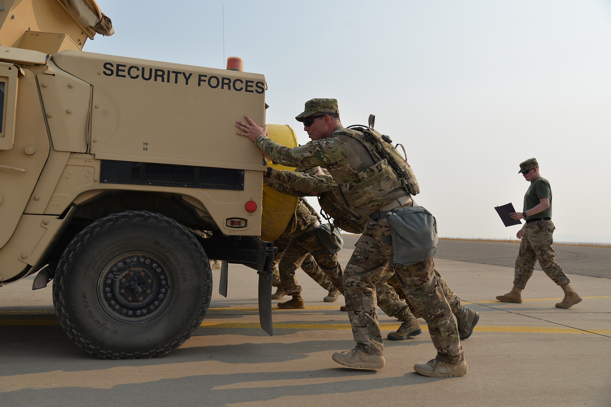 A team of security forces Airmen push a Humvee during the annual Aces Cop Combat Challenge Sept. 8, 2017, at Malmstrom Air Force Base, Mont. Teams had to push the Humvee from one side of the flight line to the other. (U.S. Air Force photo/Airman 1st Class Daniel Brosam)