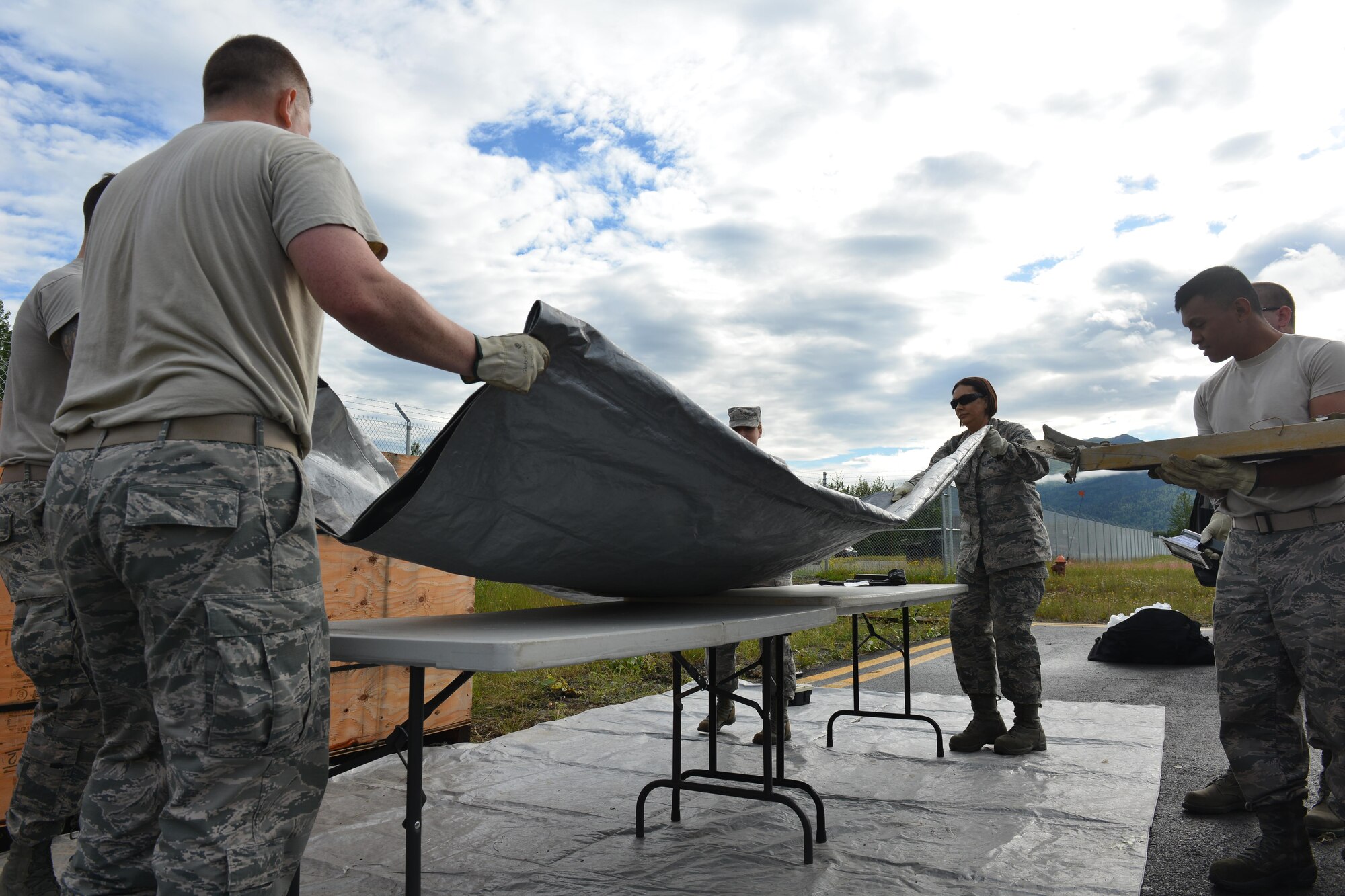 Airmen from the 673d Medical Group's Bioenvironmental Engineering Flight unload scrap metal from shipment boxes on the Bryant Army Airfield July 20, 2017.