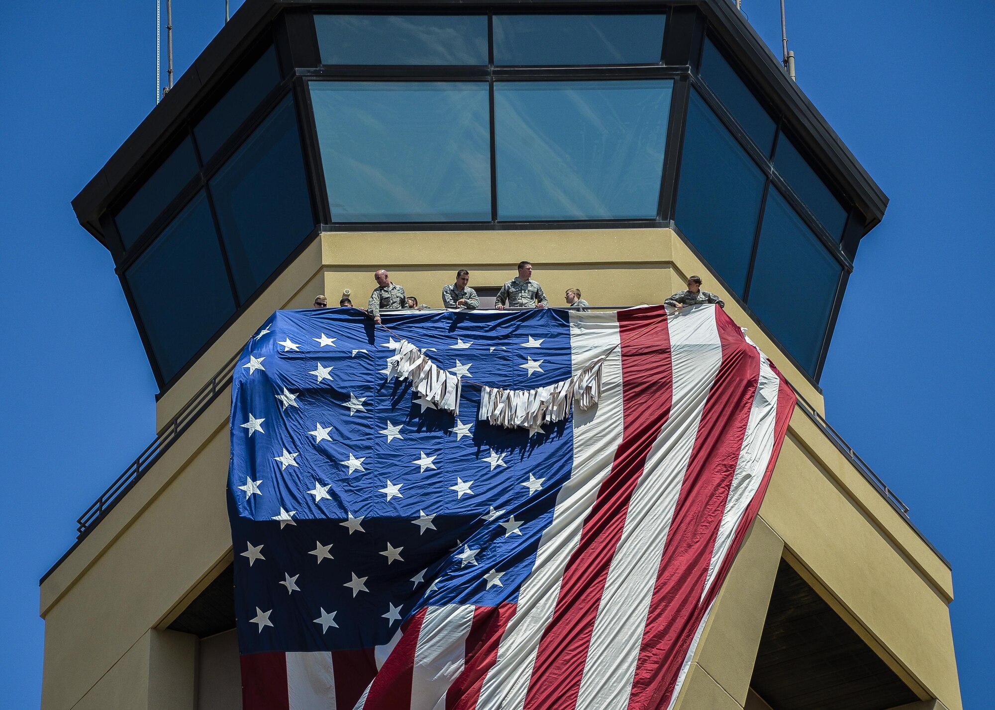 Airmen assigned to the 56th Fighter Wing display the American Flag from the air traffic control tower during Team Luke’s 9/11 remembrance ceremony Sept. 11, 2017 at Luke Air Force Base, Ariz. The ceremony included a flag unfurling, a moment of silence and a ten story stair climb honoring those killed during the terrorist attacks on Sept. 11, 2001.  (U.S. Air Force photo/Airman 1st Class Caleb Worpel)