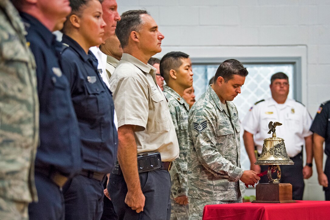 An airman chimes a bell while others stand at attention.
