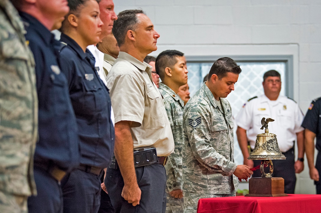An airman chimes a bell while others stand at attention.