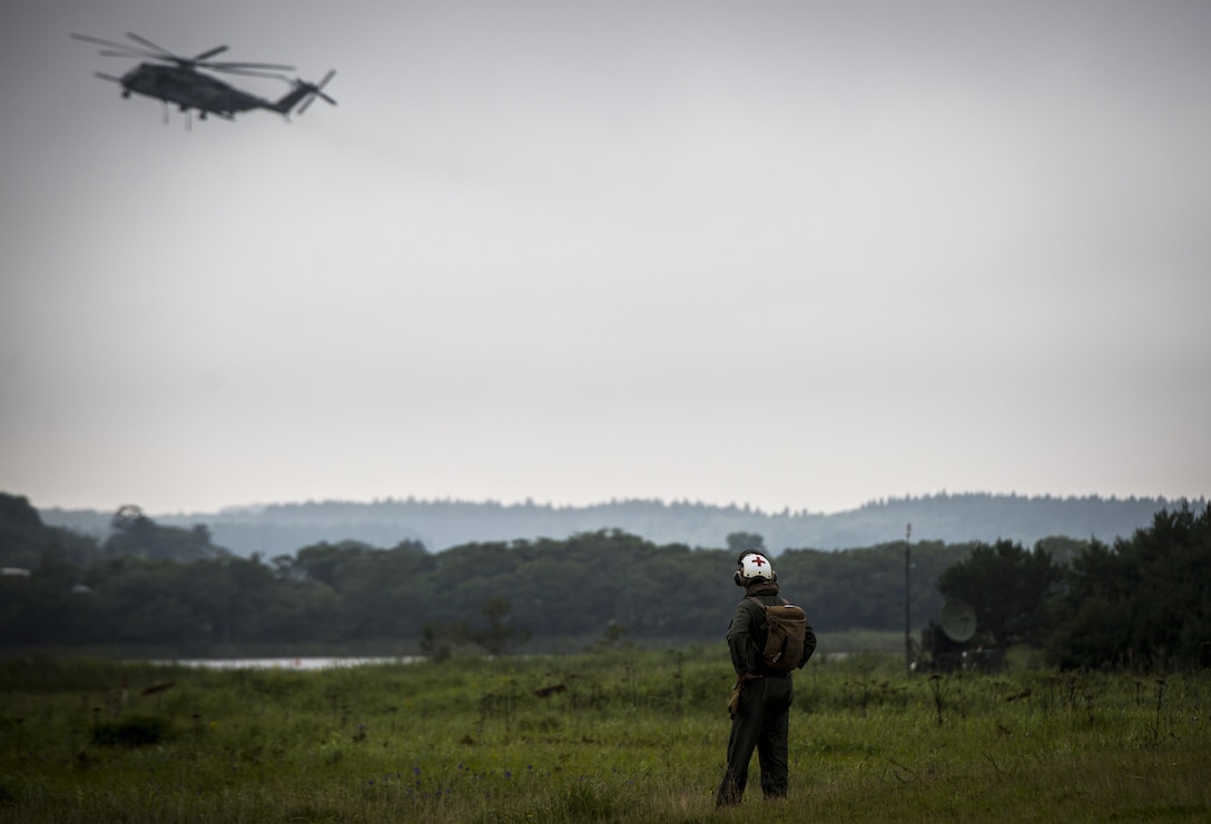 A U.S. Navy Corpsman observes a CH-53E Super Stallion at Draughon Range near Misawa Air Base, Japan, August 21, 2017, during external lift training in support of exercise Northern Viper 17. This combined-joint exercise is held to enhance regional cooperation between participating nations to collectively deter security threats. (U.S. Marine Corps photo by Lance Cpl. Andy Martinez)