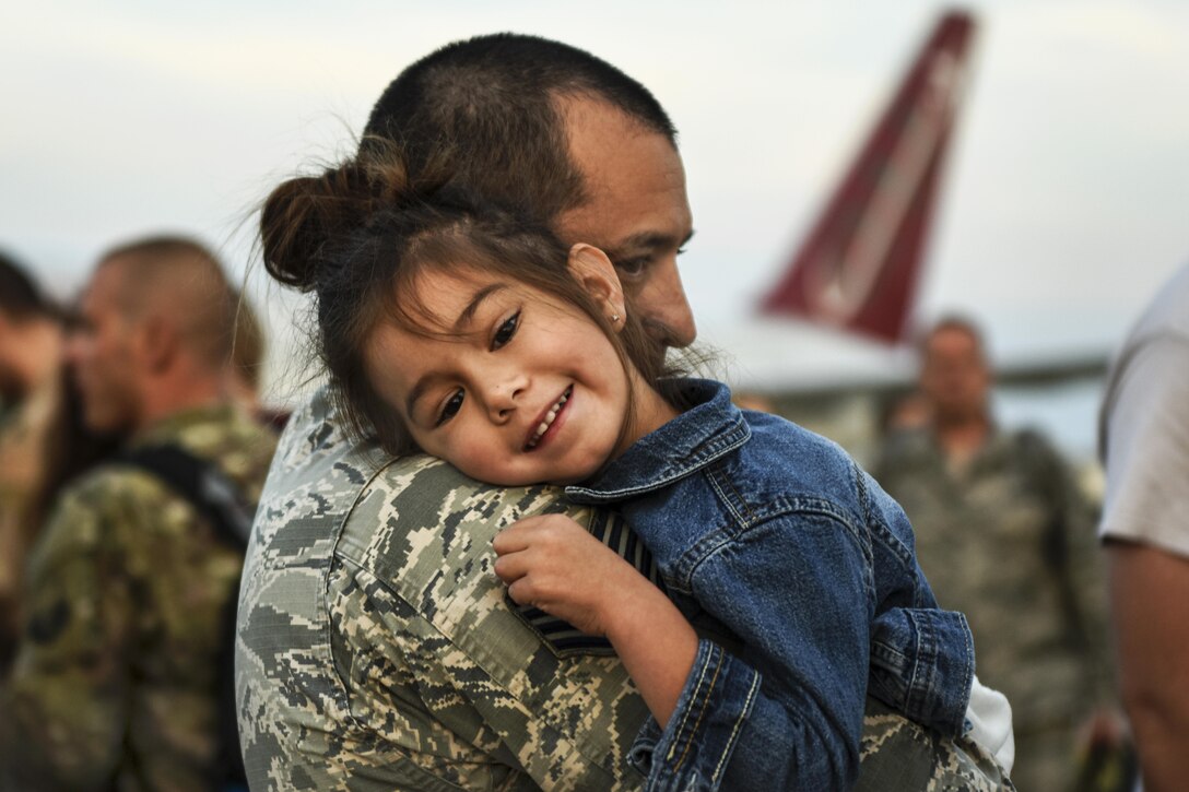 A father hugs his smiling daughter