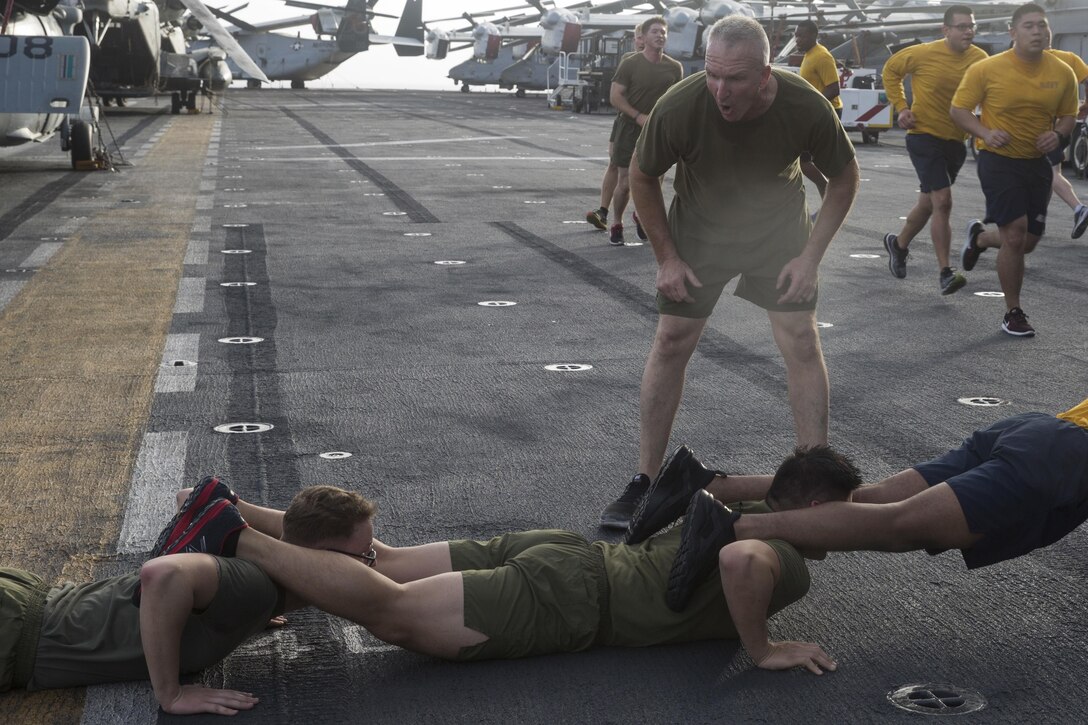 Sgt. Maj. Jim Lanham, sergeant major of the 31st Marine Expeditionary Unit, motivates Marines and Sailors with the Bonhomme Richard Expeditionary Strike Group during squad push-ups on the flight deck of the USS Bonhomme Richard (LHD 6), Sept. 9, 2017.