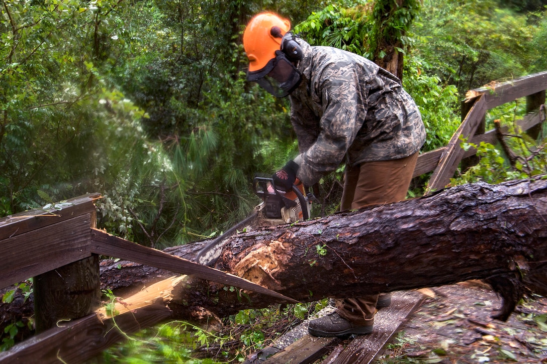 An airman uses a chainsaw