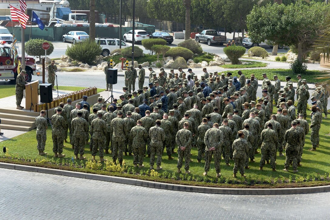 A crowd of service members holding their heads down for a moment of silence.