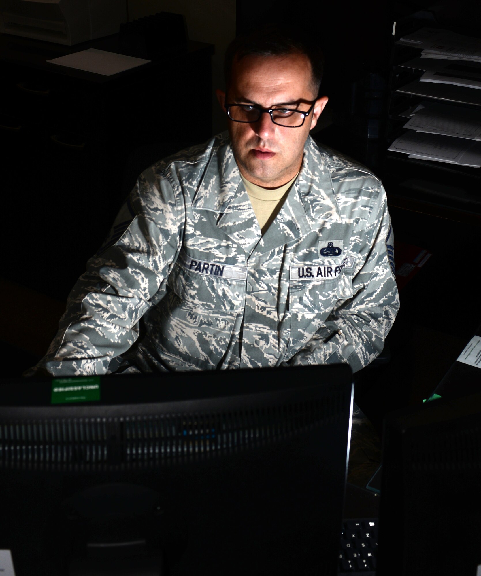 Master Sgt. Leon Partin, the unit deployment manager assigned to the 28th Operations Support Squadron, checks emails on his computer Aug. 14, 2017, on Ellsworth Air Force Base, S.D. Squadron UDMs often stay after work to ensure that Airmen who are deploying have all the necessary equipment, training and paperwork. (U.S. Air Force photo by Airman 1st Class Thomas Karol)