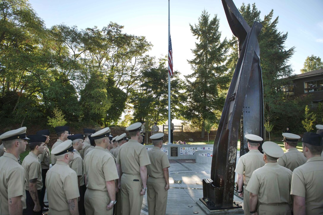 Sailors stand at attention as the flag is raised to half-mast during a 9/11 remembrance ceremony