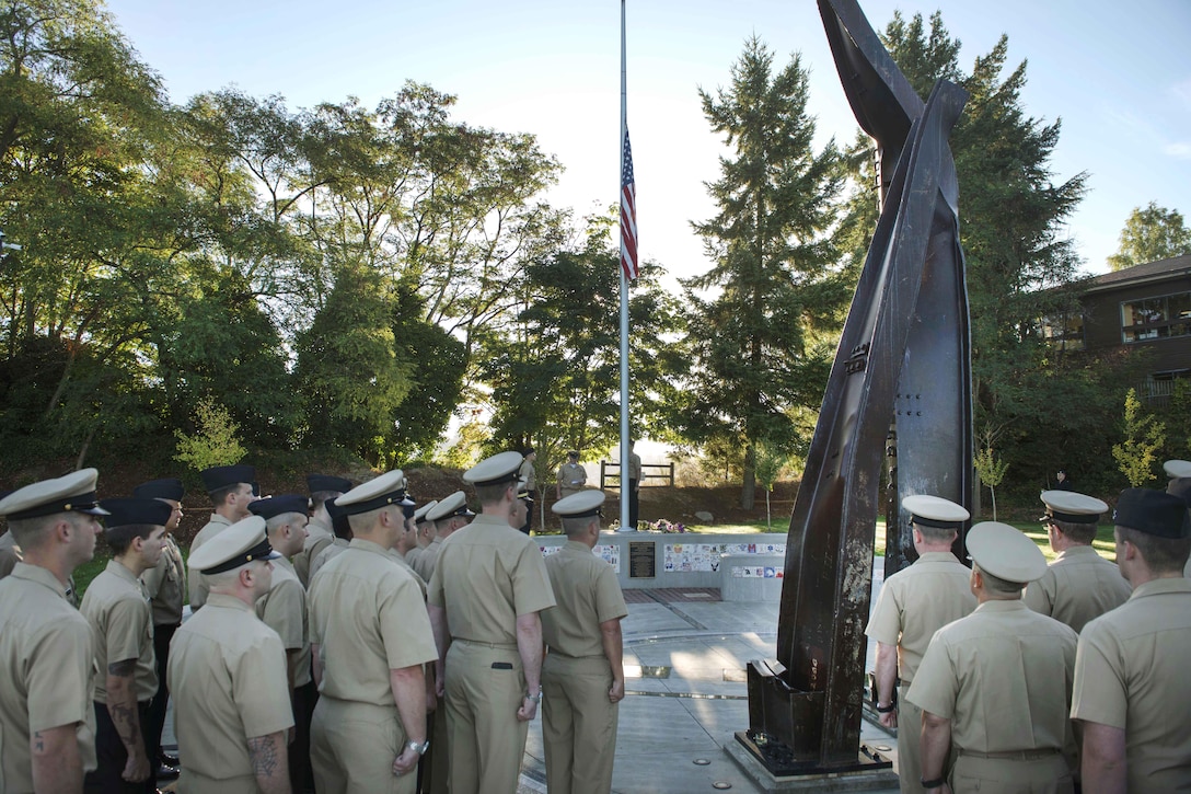 Sailors stand at attention as the flag is raised to half-mast during a 9/11 remembrance ceremony