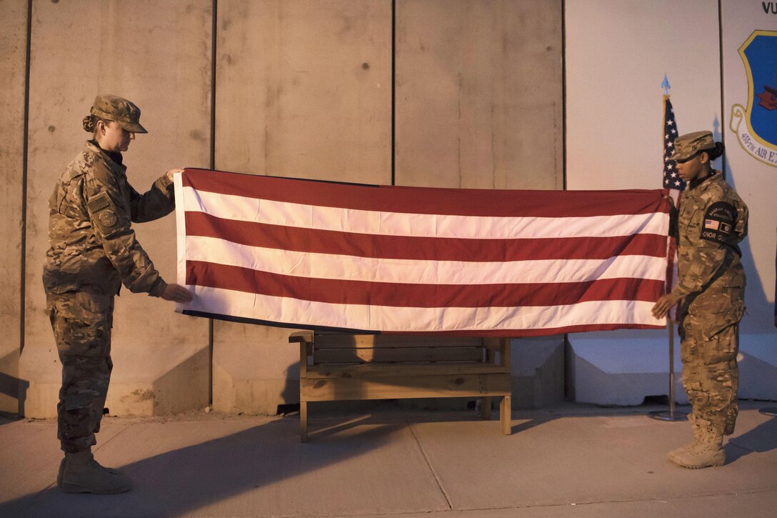 Two airmen fold the U.S. flag during a 9/11 ceremony.