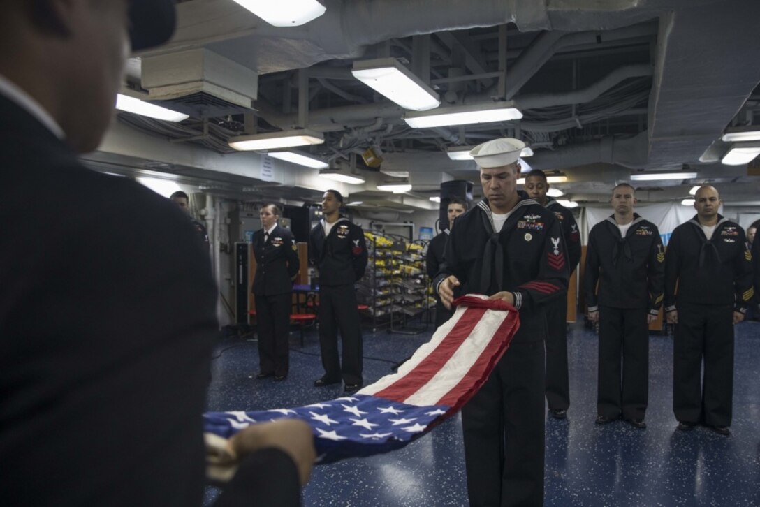 Petty Officer 1st Class Imre Balazsi folds the national ensign during a 9/11 remembrance ceremony aboard the multipurpose amphibious assault ship USS Bataan