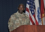Three-star Army general, facing viewer, at lecturn, wearing fatigues.