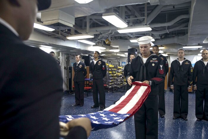 Sailors fold the American flag.