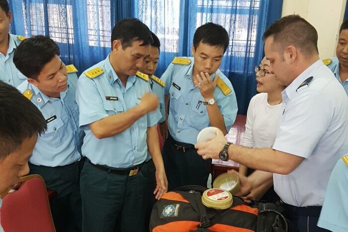 An American service member shows medical care equipment to Vietnamese service members.