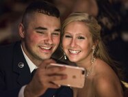 Airman 1st Class Brandon Fossett, 436th Communications Squadron cyber security technician, and his girlfriend, Becca Scott, take a selfie at their table Sept. 8, 2017, at the Rollins Center, Dover Downs Hotel and Casino, Dover, Del. The two were among the more than 800 attendees that came out for the “Wings Over Dover,” 70th Anniversary Air Force Ball, a gala-style event. (U.S. Air Force photo by Roland Balik)