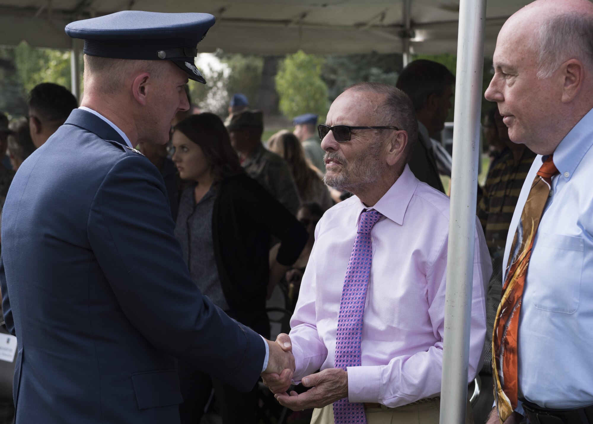 Col. Ryan Samuelson, 92nd Air Refueling Wing commander, presents a commemorative base coin to Mr. Larry Frazier (center) and Mr. Greg Staples (right), during a B-52 Stratofortress memorial ceremony at Fairchild Air Force Base, Washington, Sept. 8, 2017. Frazier and Staples both entered military service despite losing family to a B-52 crash in 1958, carrying on a family legacy of military service. (U.S. Air Force Photo by Airman 1st Class Ryan Lackey)