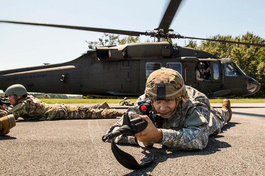 Soldiers lie on the ground with weapons during training.