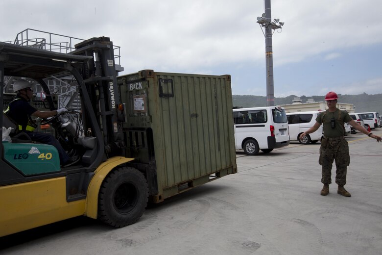 A Marine with the 31st Marine Expeditionary Unit guides a forklift pier side at White Beach Naval Facility, Okinawa, Japan, June 7, 2017.