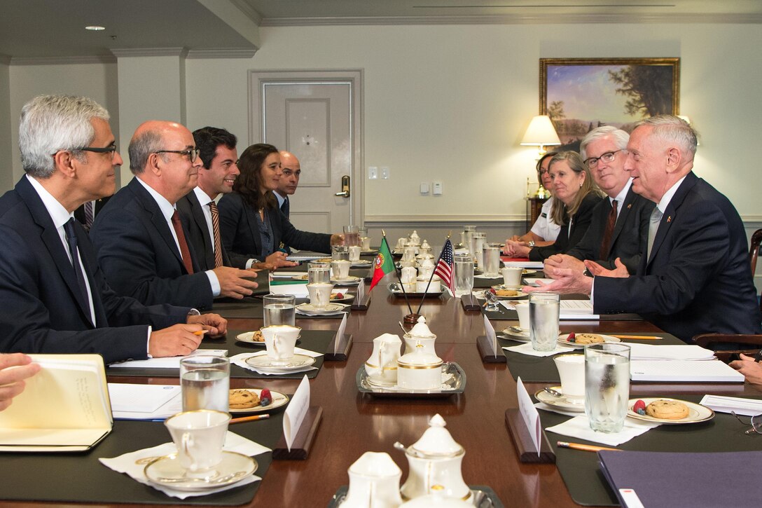 Defense Secretary Jim Mattis sits at a table with a group of people.