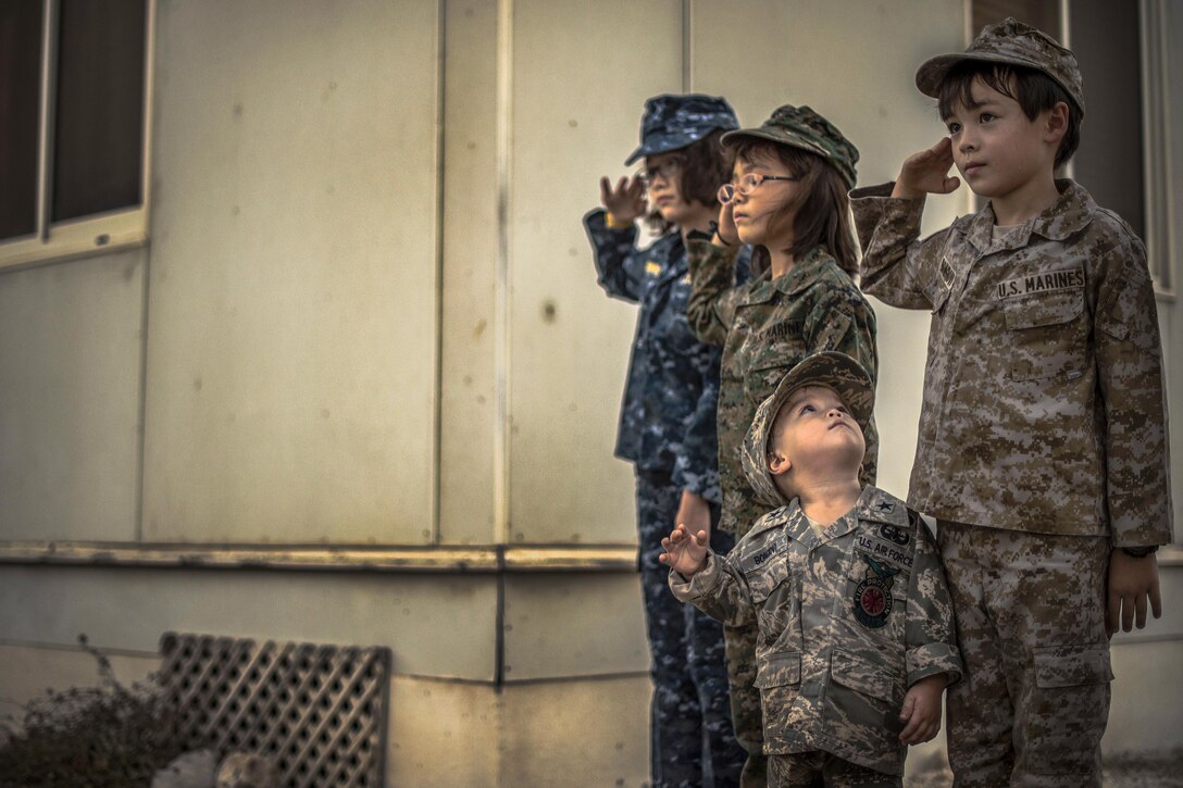 Four children in military uniforms participate in a ceremony.