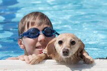 A dog rests the edge of the pool with its owner during the Dog Days of Summer event at Yokota Air Base, Japan, Sept. 9, 2017.