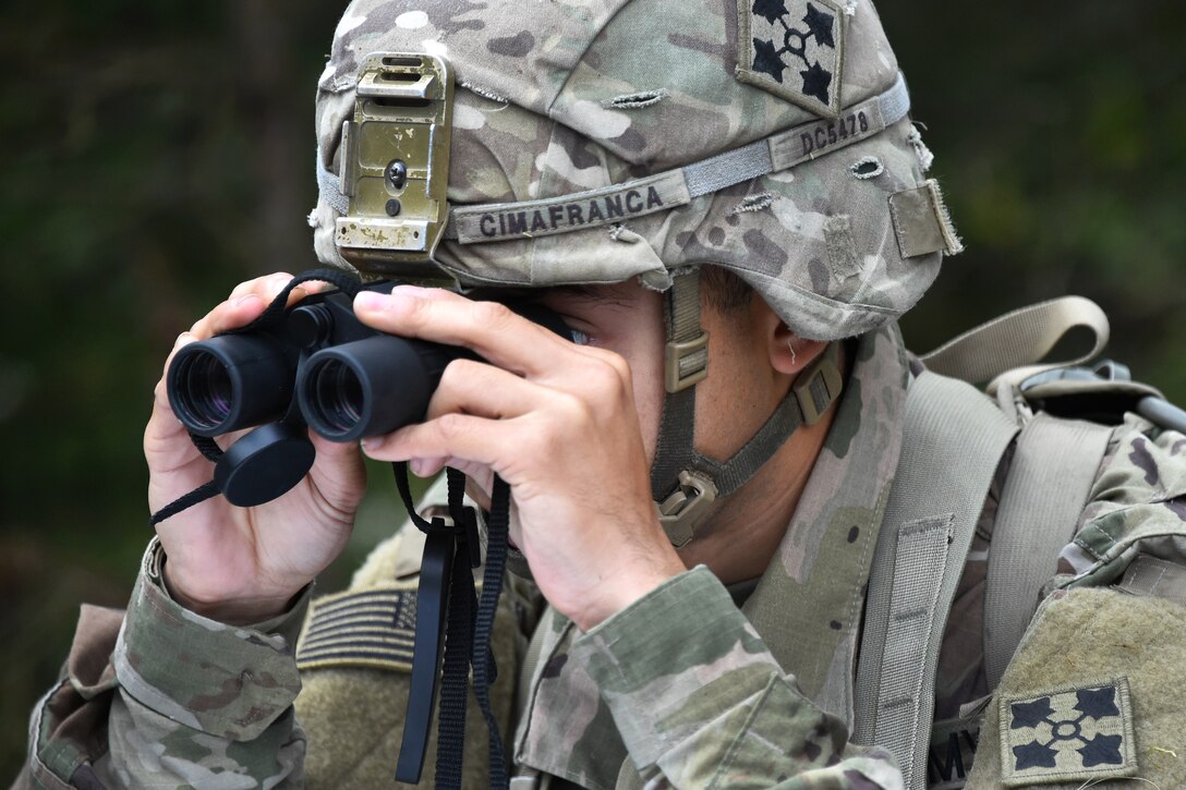 A soldier uses binoculars to locate his next objective participating in the Expert Infantryman Badge competition.