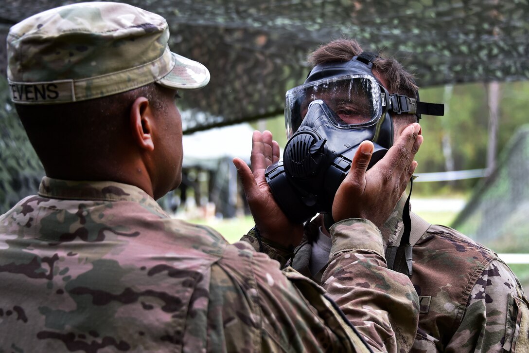 A soldier helps another with testing a gas mask during the Expert Infantryman Badge competition