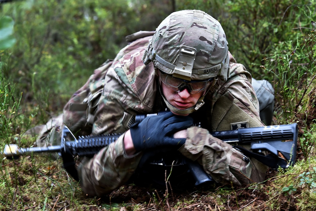 A soldier does a low crawl to the next station during the Expert Infantryman Badge competition.