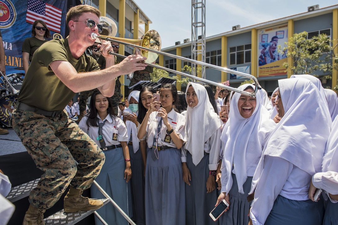 A Marine plays the trombone to smiling students in Indonesia.