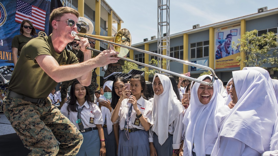 A Marine plays the trombone to smiling students in Indonesia.