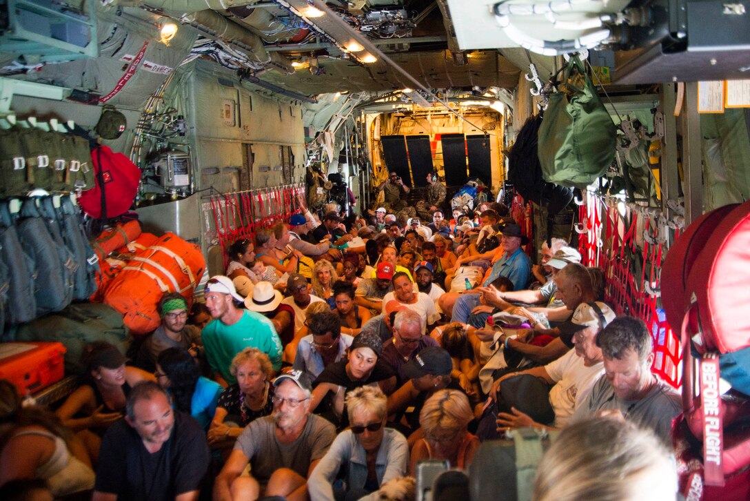 Evacuees sit on the floor of a HC-130 Hercules aircraft.