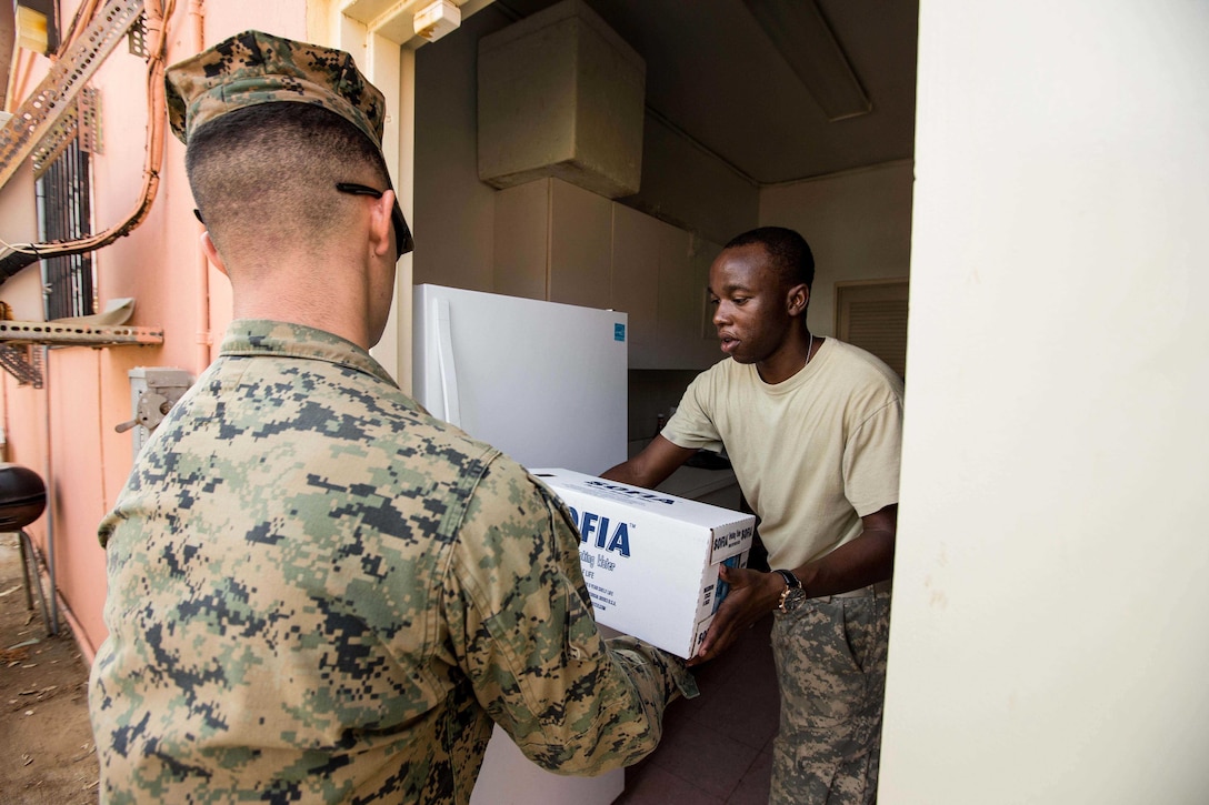 A U.S. Marine with Battalion Landing Team 2nd Battalion, 6th Marine Regiment, 26th Marine Expeditionary Unit (MEU), delivers water to a U.S. Virgin Islands Army National Guard soldier for victims of Hurricane Irma at the Ramona Blades Community Center, St. Thomas, U.S. Virgin Islands, Sept. 12, 2017. The 26th MEU is supporting the lead federal agency in providing humanitarian relief (and/or search and rescue) efforts for Hurricane Irma. (U.S. Marine Corps photo by Lance Cpl. Tojyea G. Matally)