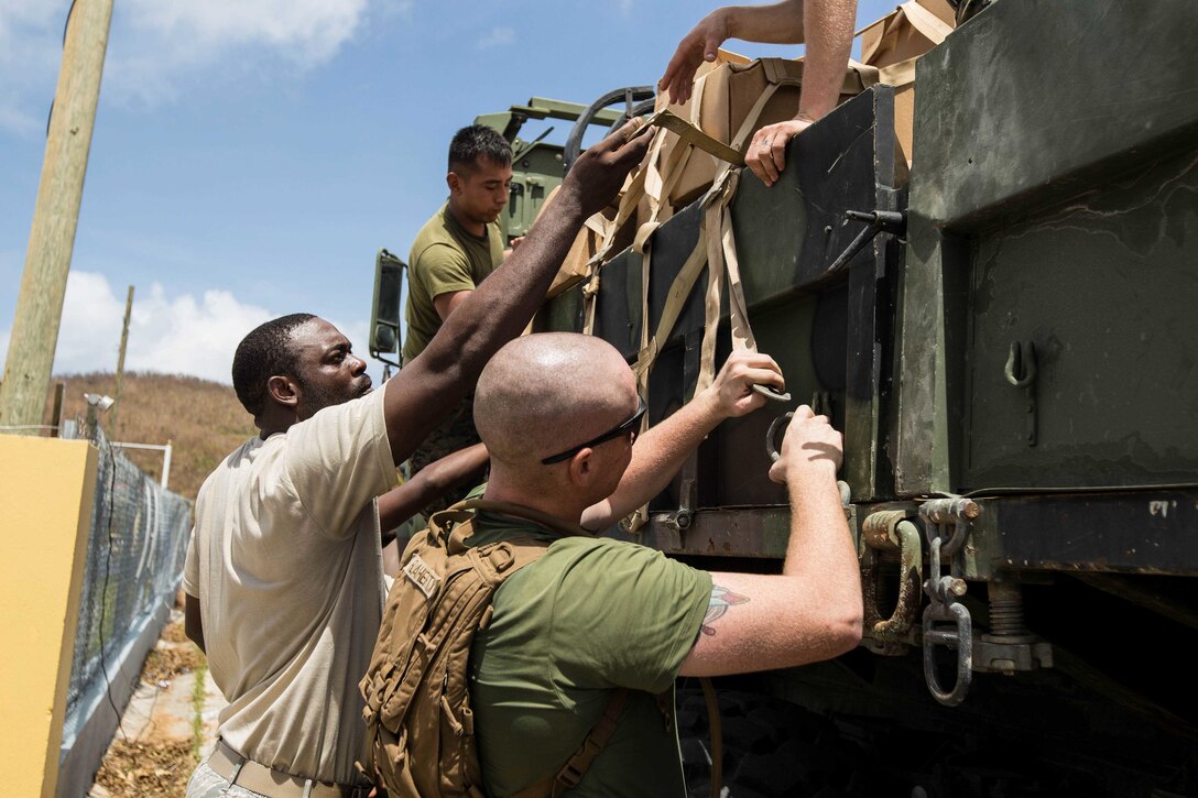 U.S. Marines with Battalion Landing Team 2nd Battalion, 6th Marine Regiment, 26th Marine Expeditionary Unit (MEU), and a U.S. Virgin Islands Army National Guard soldier, tie down a ratchet strap over the bed of an Medium Tactical Vehicle Replacement to continue delivering food for victims of Hurricane Irma in St. Thomas, U.S. Virgin Islands, Sept. 12, 2017. The 26th MEU is supporting the lead federal agency in providing humanitarian relief (and/or search and rescue) efforts for Hurricane Irma. (U.S. Marine Corps photo by Lance Cpl. Tojyea G. Matally)