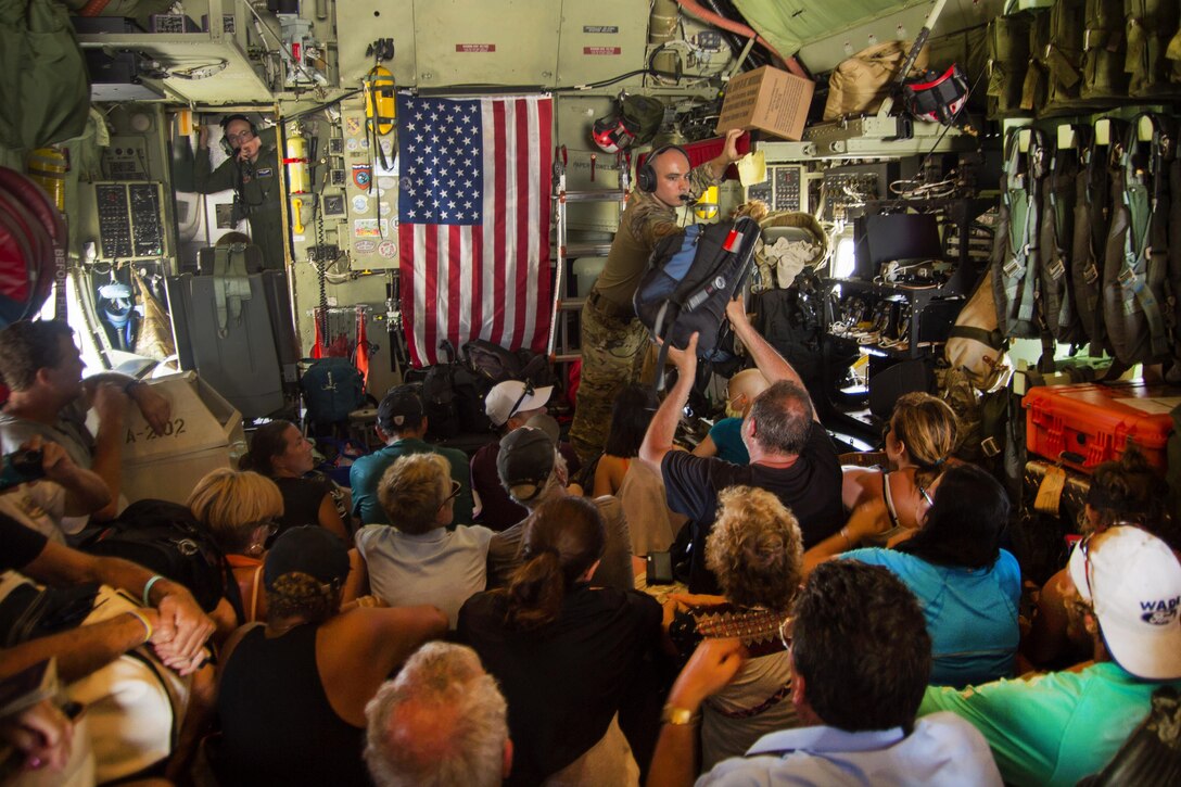 An airman hands a person a bag while inside an aircraft.