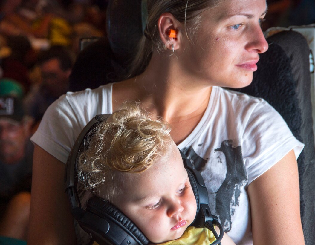 A mother holding her child looks out the window of an aircraft.