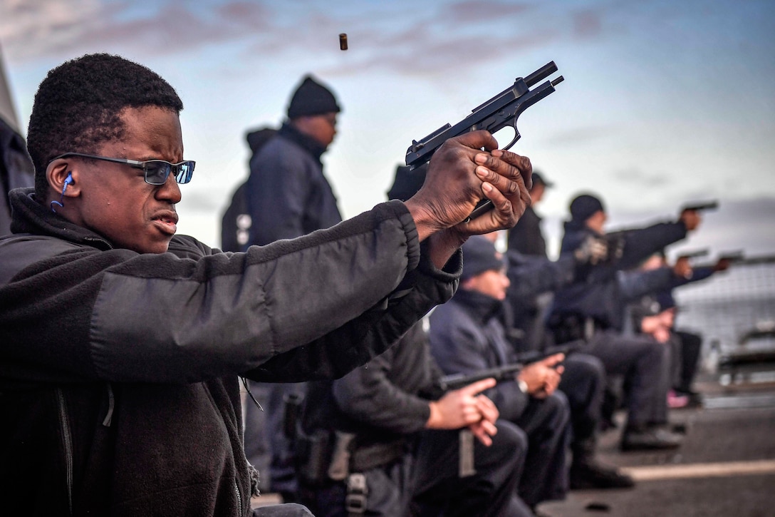 A sailor fires a pistol on a ship, as a line of sailors points