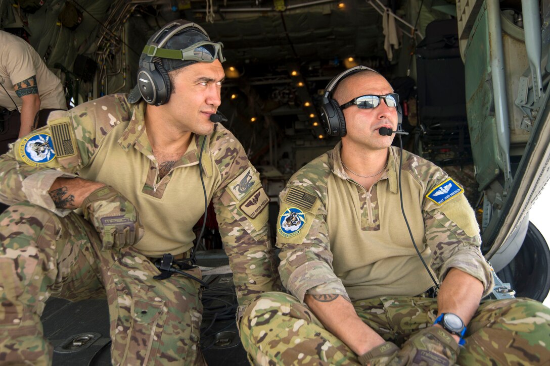 Two airmen sit on the back of an airplane.