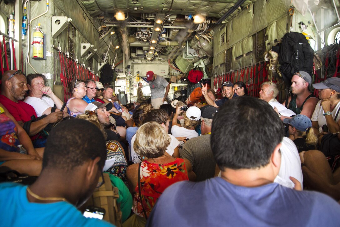 Evacuees sit on the floor of an aircraft.