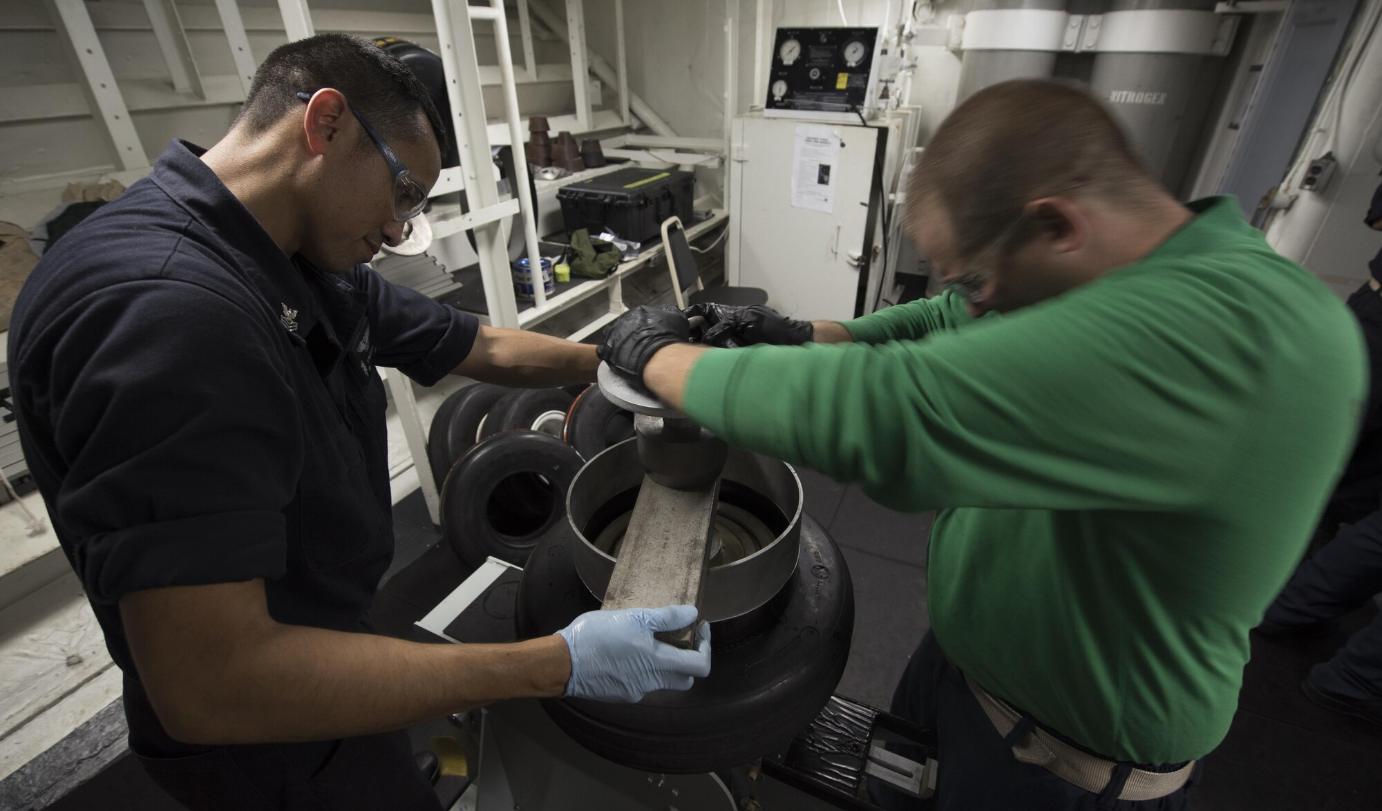 U.S. Navy Aviation Structural Mechanic 1st Class Dynasty Palaganus, USS Abraham Lincoln (CVN 72) and U.S. Air Force Staff Sgt. Mark Gower, 33rd Maintenance Squadron wheel and tire technician, disassemble an F-35C Lightning II nose wheel Sept. 6, 2017, aboard the ship. Two Airmen and two Sailors from 33rd MXS qualified Abraham Lincoln Sailors to operate F-35 support equipment bringing the U.S. Navy one step closer to initial operations capability. (U.S. Air Force photo by Staff Sgt. Peter Thompson/Released)