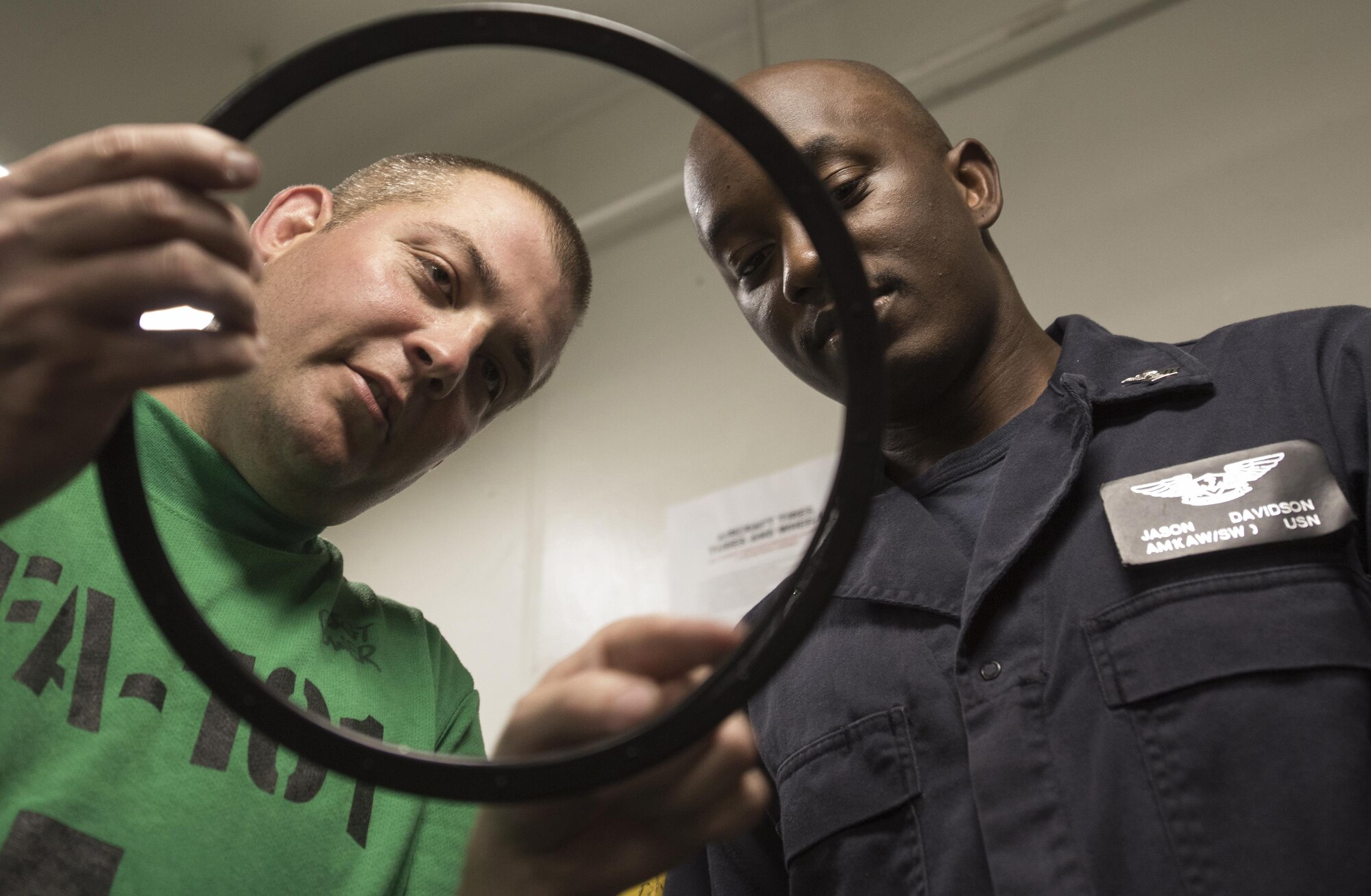 U.S. Air Force Staff Sgt. Mark Gower, 33rd Maintenance Squadron wheel and tire technician, and U.S. Navy Aviation Structural Mechanic 1st Class Jason Davidson, USS Abraham Lincoln (CVN 72) inspect an external seal from an F-35C Lightning II nose wheel Sept. 6, 2017, aboard the ship. Two Airmen and two Sailors from 33rd MXS qualified Abraham Lincoln Sailors to operate F-35 support equipment bringing the U.S. Navy one step closer to initial operations capability. (U.S. Air Force photo by Staff Sgt. Peter Thompson/Released)