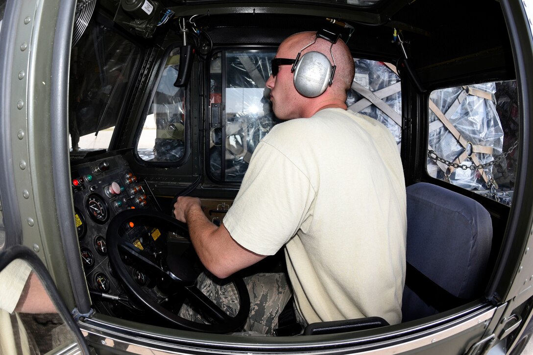 An airman controls the movement of uploading equipment and palletized cargo onto a C-17A Globemaster III.