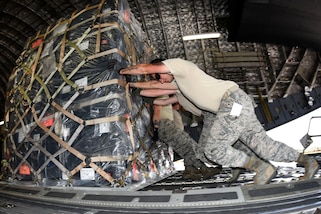 Airmen push palletized cargo onto a C-17A Globemaster III