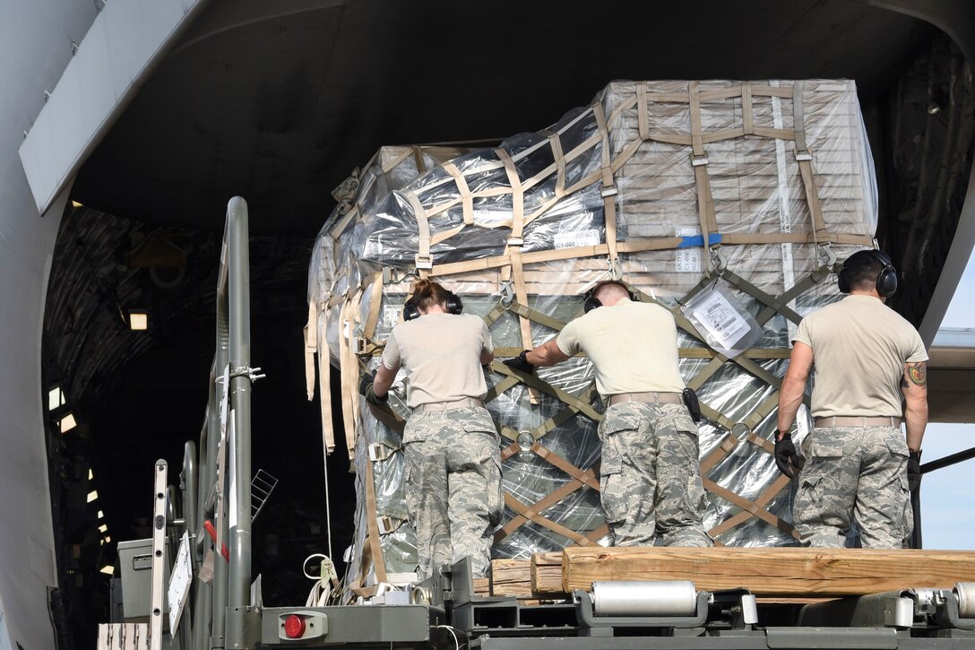 Airmen push palletized cargo onto a C-17A Globemaster III