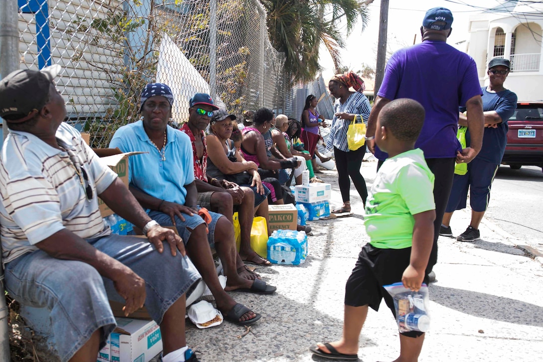 Virgin Islanders talk after receiving water and food distributed by Virgin Islands Army National Guardsmen