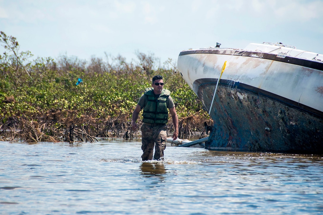 Sgt. John Shannon wades back to his Zodiac boat after tagging an abandoned sailboat.